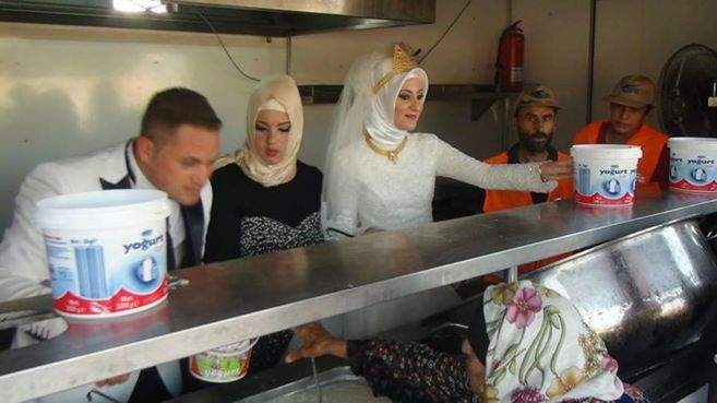 Fethullah Üzümcüolu y Esra Polat dando comida a una refugiada siria, en Kilis. KYM
